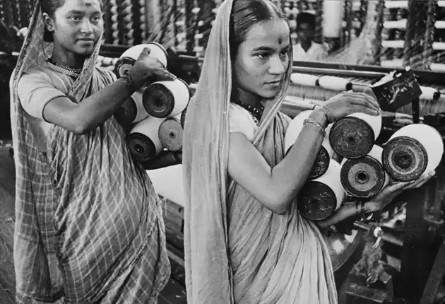 Women workers carrying spindles in factory