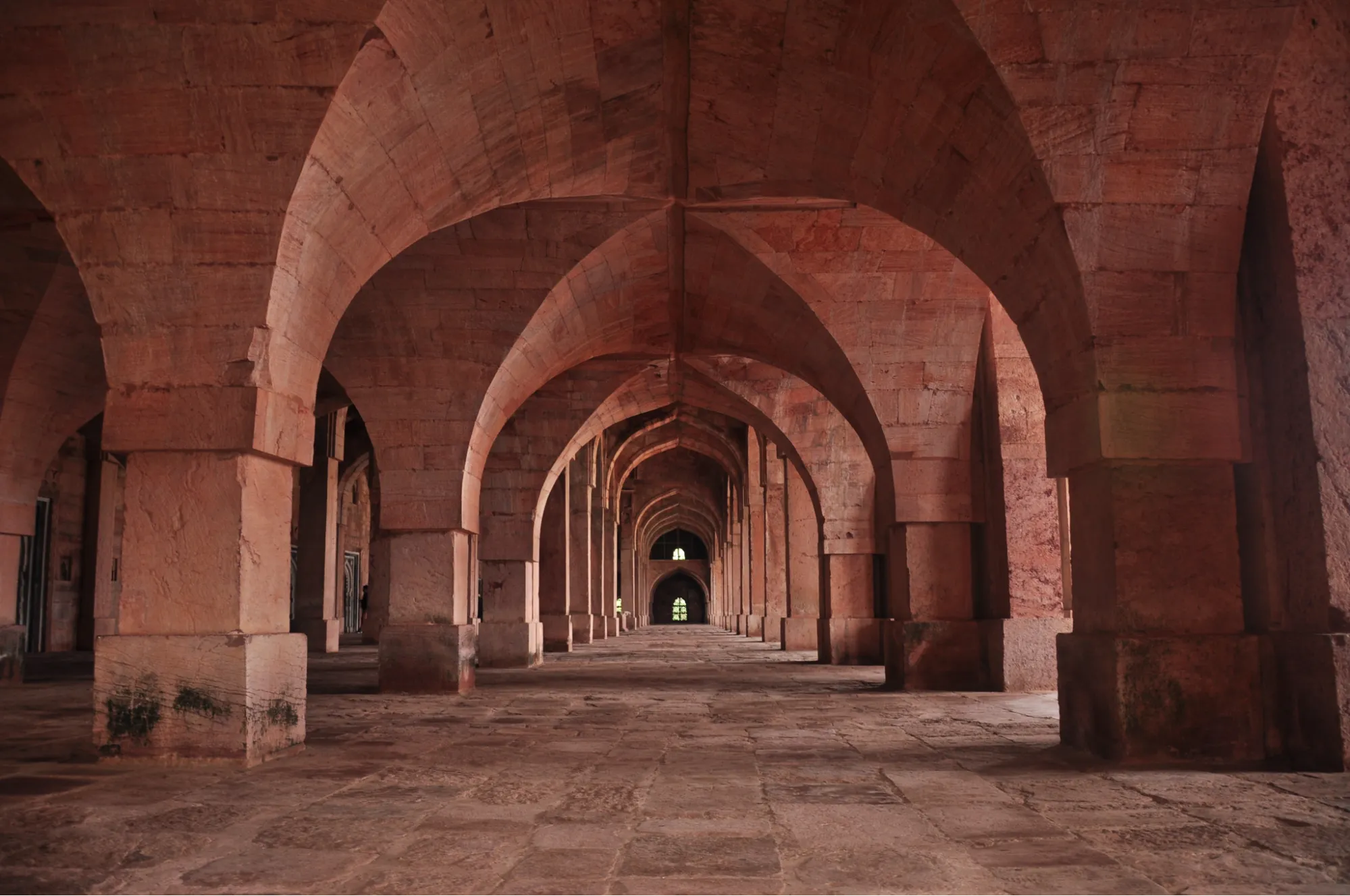 Ancient stone archway corridor in Mandu, Madhya Pradesh showcasing Indo-Islamic architecture.