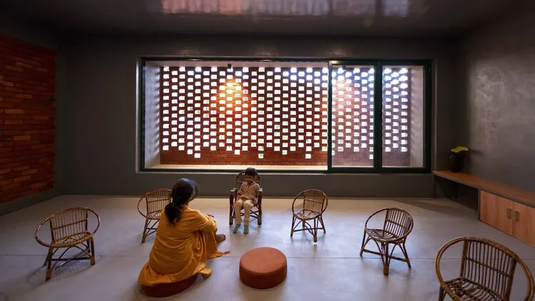 Minimalist indoor space with natural lighting, jali brick screen, and rattan furniture in a modern Indian home