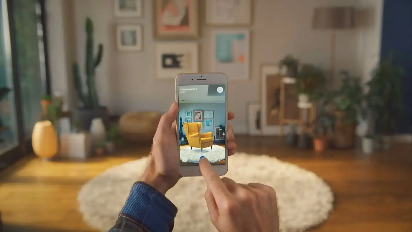 Person using a phone to preview a yellow armchair in their living room.